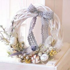 a white wreath decorated with feathers and flowers on top of a shelf in front of a door