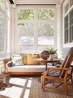 the sun shines through two large windows into a porch with white walls and wood flooring