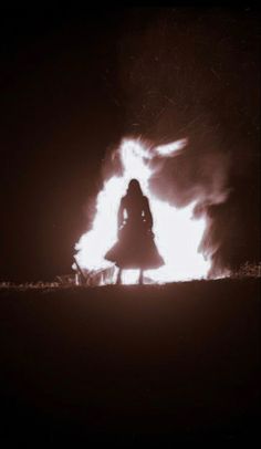 a woman standing in front of a fire