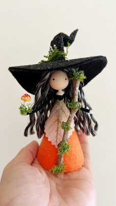 a hand holding a tiny doll with a witches hat