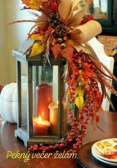 a lantern with candles and fall decorations on the table in front of a plate full of food