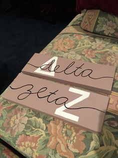 two wooden signs sitting on top of a floral covered bed frame with the word delta blvd