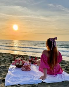 a woman sitting on top of a towel near the ocean