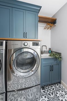 a washer and dryer in a laundry room with blue cabinetry on the walls