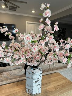 a vase filled with pink flowers sitting on top of a wooden table next to a couch