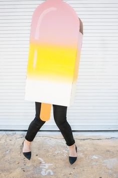 a woman is walking down the street with an ice cream cone shaped costume on her head