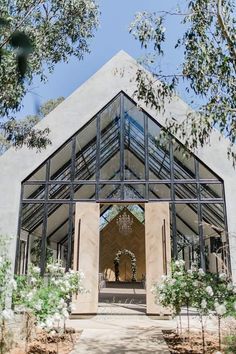 the inside of a building that is surrounded by trees and flowers, with an entry way leading into it