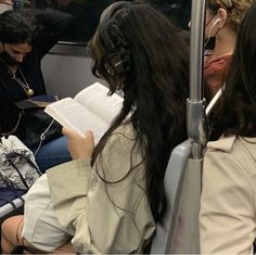 some people sitting on a train and one is reading a book