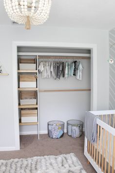 a baby's closet with clothes hanging on the wall and two baskets in front of it