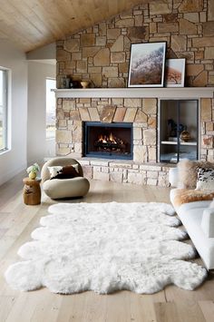 a living room filled with furniture and a fire place next to a stone wall covered in pictures