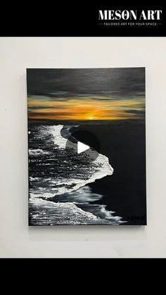 a painting hanging on the wall next to a white wall with an orange and black sunset