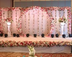 a table with flowers and candles on it in front of a wall decorated with sheer curtains