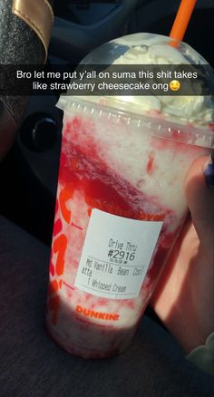 someone is holding up a drink with ice cream and strawberries on it in the car