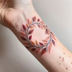 a woman's arm with a tattoo on it that has leaves in the shape of a circle