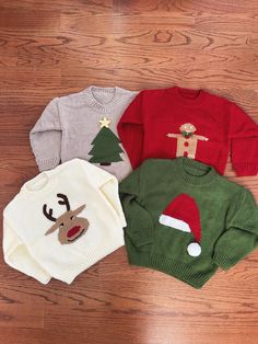 three sweaters with christmas decorations on them sitting on a wooden floor next to each other