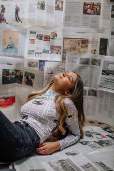 a woman laying on top of a bed covered in newspapers