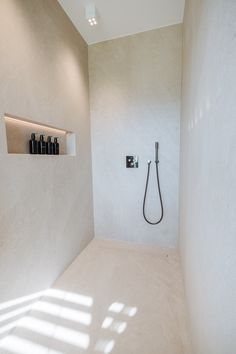 a white bathroom with a shower head and shelves