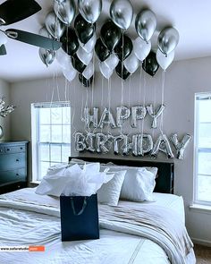 a bedroom decorated with balloons and streamers for a happy birthday message on the wall