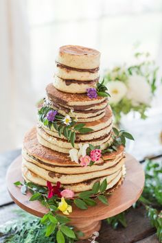 a stack of pancakes sitting on top of a wooden plate covered in flowers and greenery