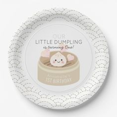 a white plate with a cartoon cat in a bowl on the front and an inscription that reads, their little dumpling is one the way