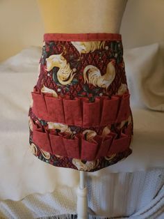 a woman's skirt made out of fabric with roosters on red and gold