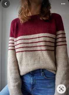 a woman wearing a red and white striped sweater with her hands in her pockets, looking at the camera