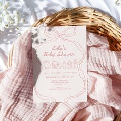 a baby shower is shown in a basket with pink blankets and flowers on the bed