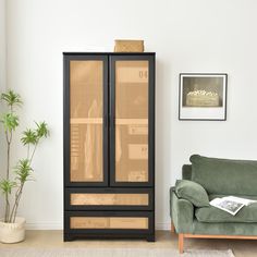 a living room with a green couch and a black cabinet in front of a white wall