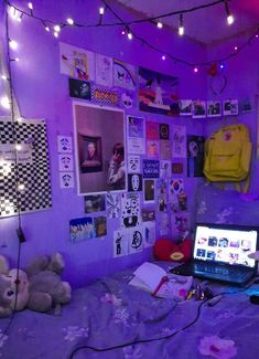 a bed room with a laptop computer on top of it and lots of pictures on the wall