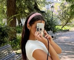 a woman is taking a photo with her camera on a bench in the city park