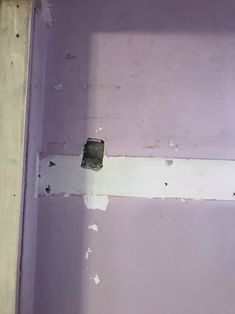 a bathroom with purple walls and peeling paint