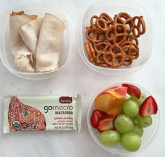 three plastic bowls filled with fruit, pretzels and other snacks on a table