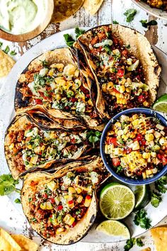 mexican food on a plate with tortillas, lime wedges and guacamole