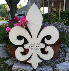 a white wooden fleur de lis sign sitting on top of a flower pot