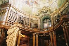 the interior of a large library with many bookshelves and paintings on the ceiling