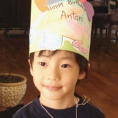 a young boy wearing a birthday hat on top of his head