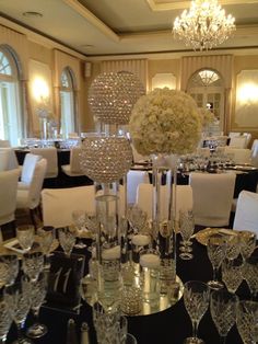 the tables are set with crystalware and white flowers in centerpieces on them