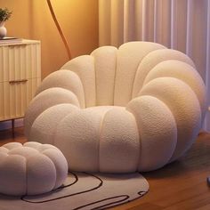 a large white chair sitting on top of a wooden floor next to a lamp and rug