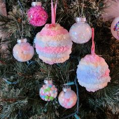 christmas ornaments hanging from a tree with pink, white and blue decorations on it's branches