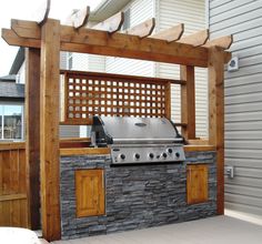 an outdoor bbq with grill and pergolated area in front of a house