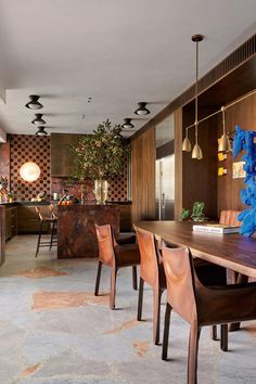 a dining room table and chairs in front of a wall with decorative artwork on it