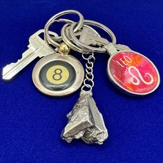 a metal key chain with two keys attached to it and a piece of rock on the other side