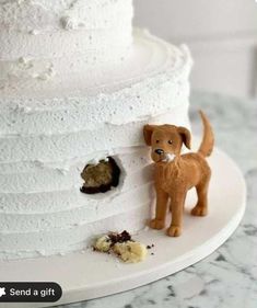 there is a small dog figurine on top of a white tiered cake