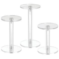 three clear glass tables with metal bases on each side and one in the middle, set against a white background