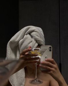 a woman is taking a selfie in the mirror with her wine glass and towel over her head