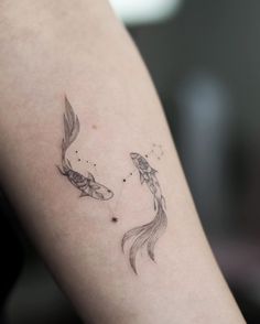 a woman's arm with two fish tattoo on the left side of her body