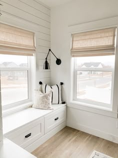 a white room with two windows and some pillows