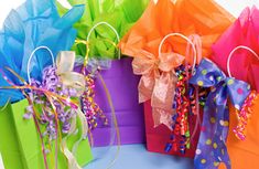 colorful gift bags with ribbons and confetti on them