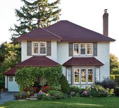 a large white house with lots of windows and plants on the front lawn in front of it