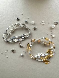 three bracelets with beads and charms on top of a white table next to a cup